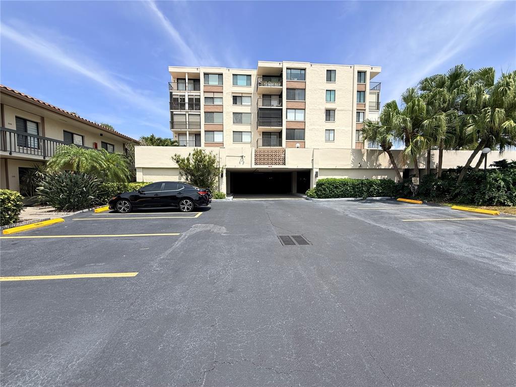 A multi-story apartment building features a ground-level parking garage and an adjacent paved lot — 6219 PALMA DEL MAR BOULEVARD S UNIT 504, ST PETERSBURG, FL