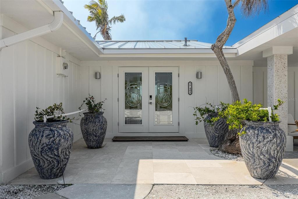 The exterior entrance features double glass doors, four large blue patterned planters, and stone flooring — 2740 N BEACH ROAD UNIT B, ENGLEWOOD, FL