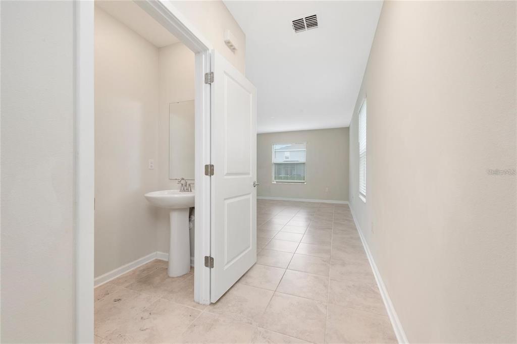 A small powder room with a pedestal sink opens into a tiled living area — 2843 ALDER BERRY BOULEVARD, OCOEE, FL