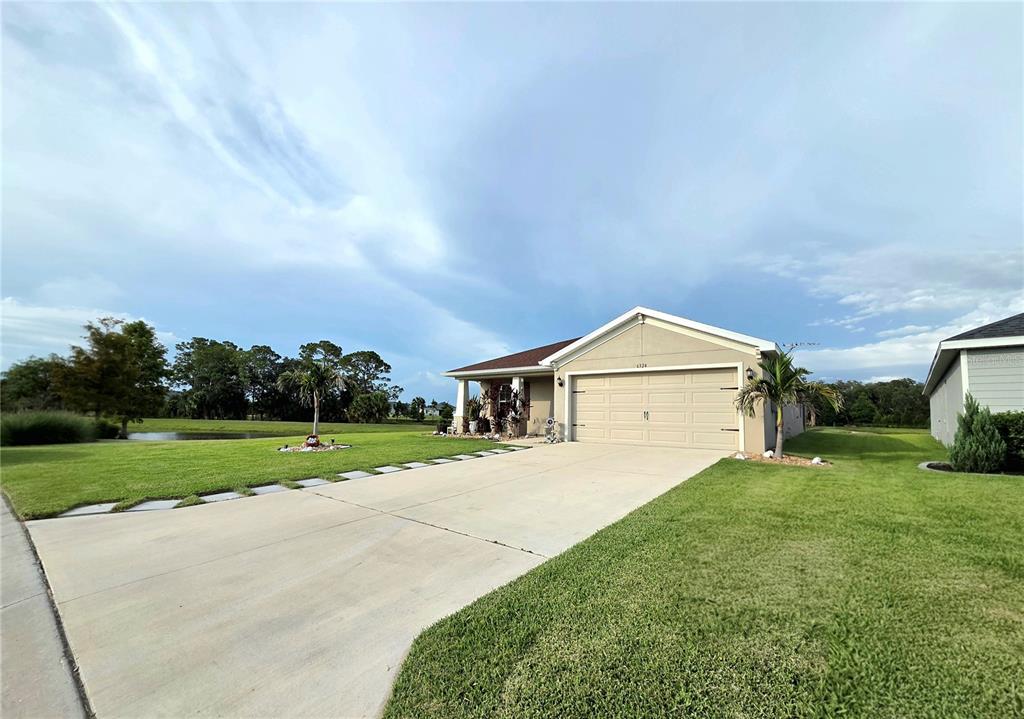 A single-story house with a two-car garage, a palm tree, and a grassy front yard — 6324 165TH DRIVE E, PARRISH, FL