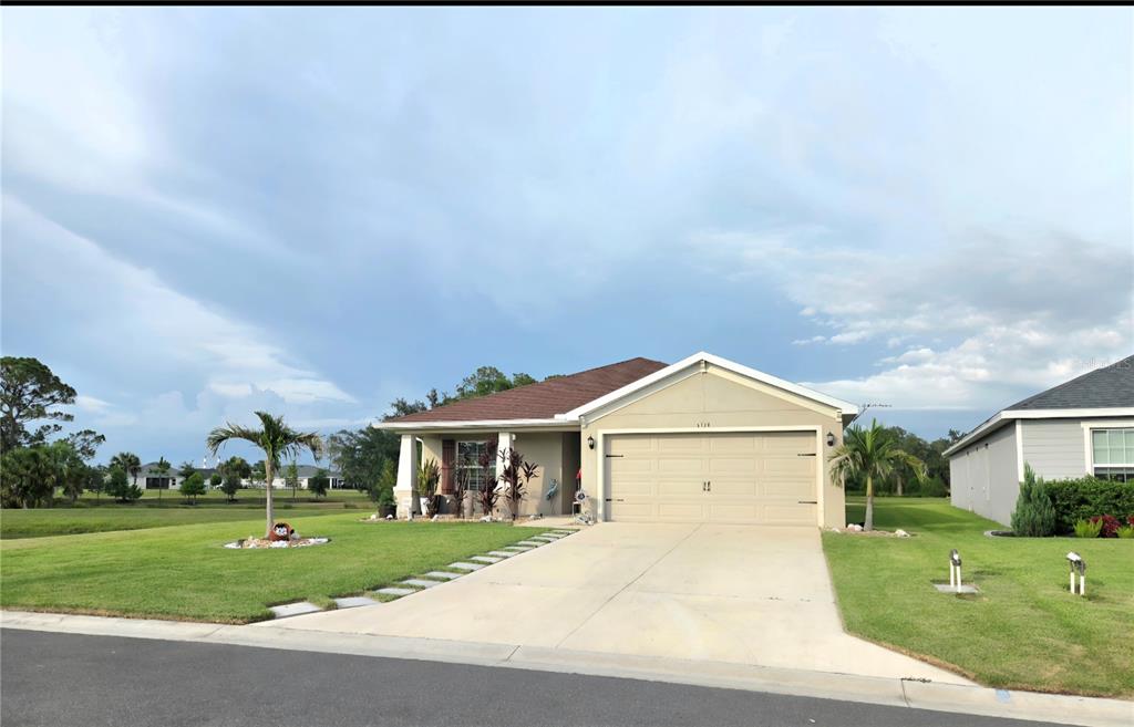 A single-story house with a tan stucco exterior, a two-car garage, and a front garden — 6324 165TH DRIVE E, PARRISH, FL