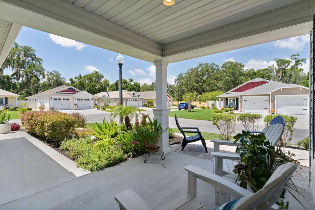 A covered front porch features concrete flooring, white columns, and views of a suburban street — 2823 CHRISTOPHER COURT, THE VILLAGES, FL