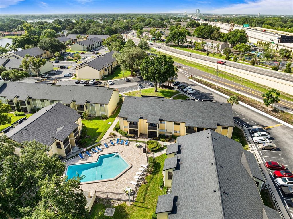 An aerial view shows apartment buildings, a swimming pool, and a nearby highway — 910 LAKE DESTINY ROAD UNIT B, ALTAMONTE SPRINGS, FL