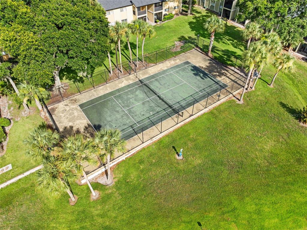 An aerial view shows a fenced tennis court surrounded by palm trees and green grass — 910 LAKE DESTINY ROAD UNIT B, ALTAMONTE SPRINGS, FL