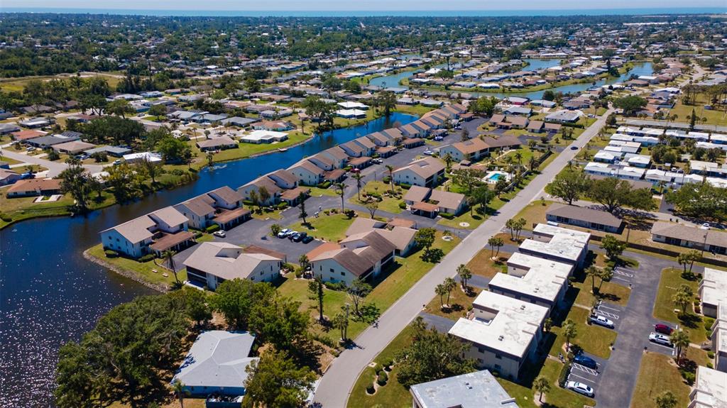 An aerial view shows multi-unit residential buildings situated along a canal in a suburban neighborhood — 1770 LAKE PLACE UNIT 1770D, VENICE, FL