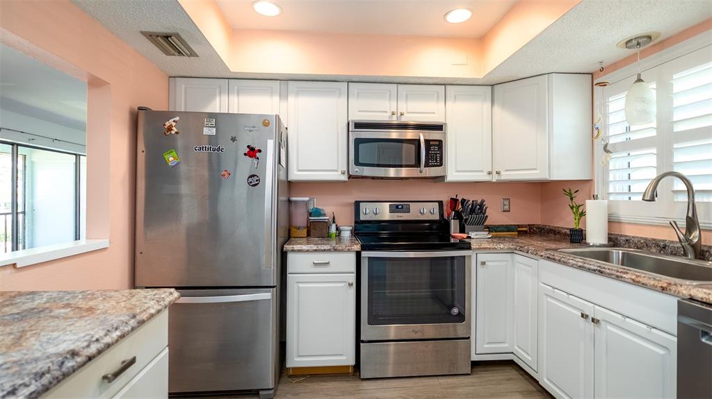 A kitchen features white cabinets, stainless steel appliances, and a brown patterned laminate countertop — 1770 LAKE PLACE UNIT 1770D, VENICE, FL