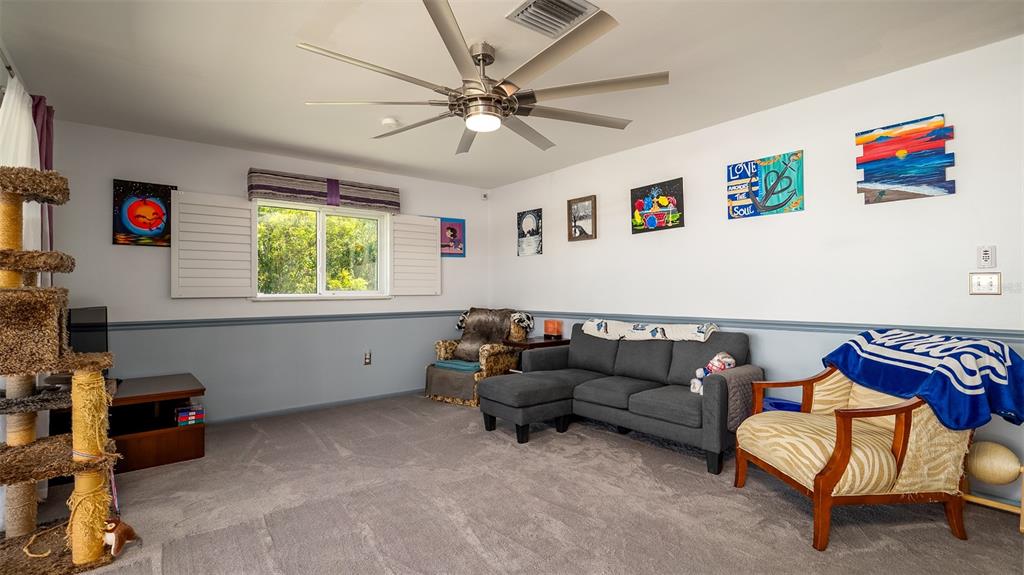 A living room features a grey sectional sofa, an armchair, a cat tree, and wall art — 1770 LAKE PLACE UNIT 1770D, VENICE, FL