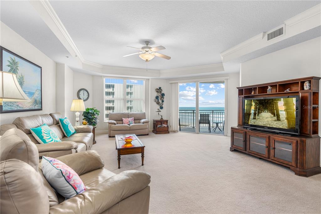 A living room features beige leather sofas, a wooden entertainment center, and a balcony overlooking the ocean — 2403 S ATLANTIC AVENUE UNIT 309, DAYTONA BEACH, FL