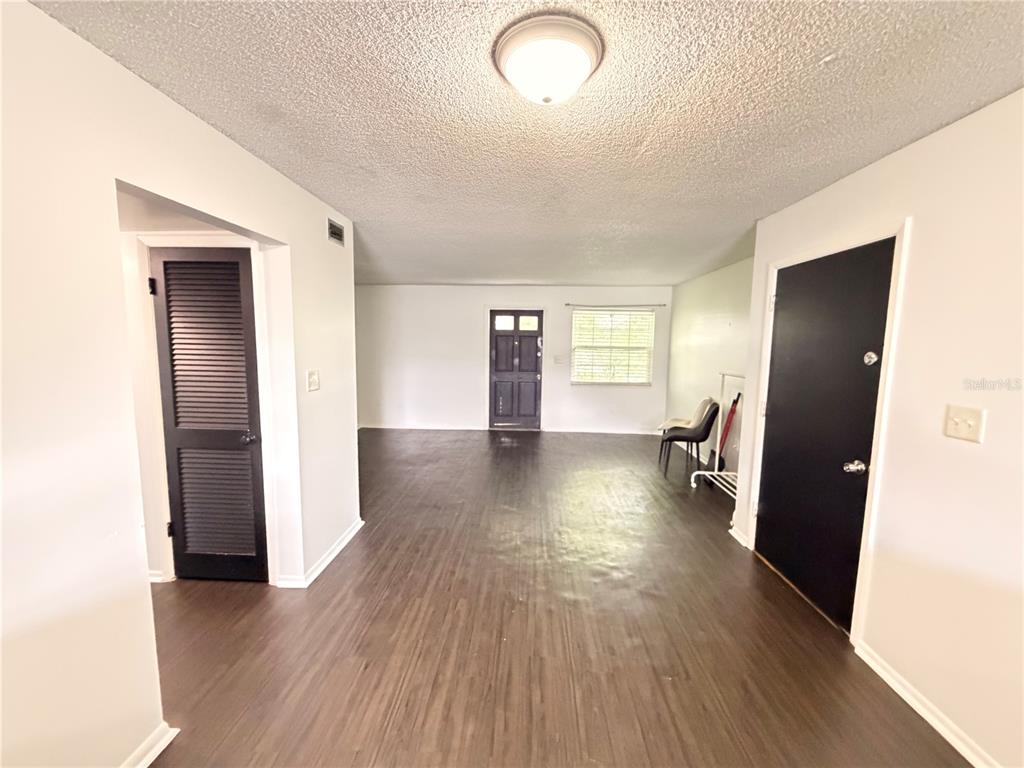 An empty room features dark wood-look flooring, white walls, a popcorn ceiling, and two black doors — 525 CONWAY ROAD UNIT 72, ORLANDO, FL