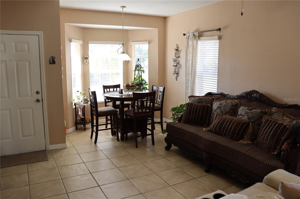 A dining area with a round table and chairs sits next to a living room sofa — 1404 LAS VILLAS BOULEVARD, SEBRING, FL