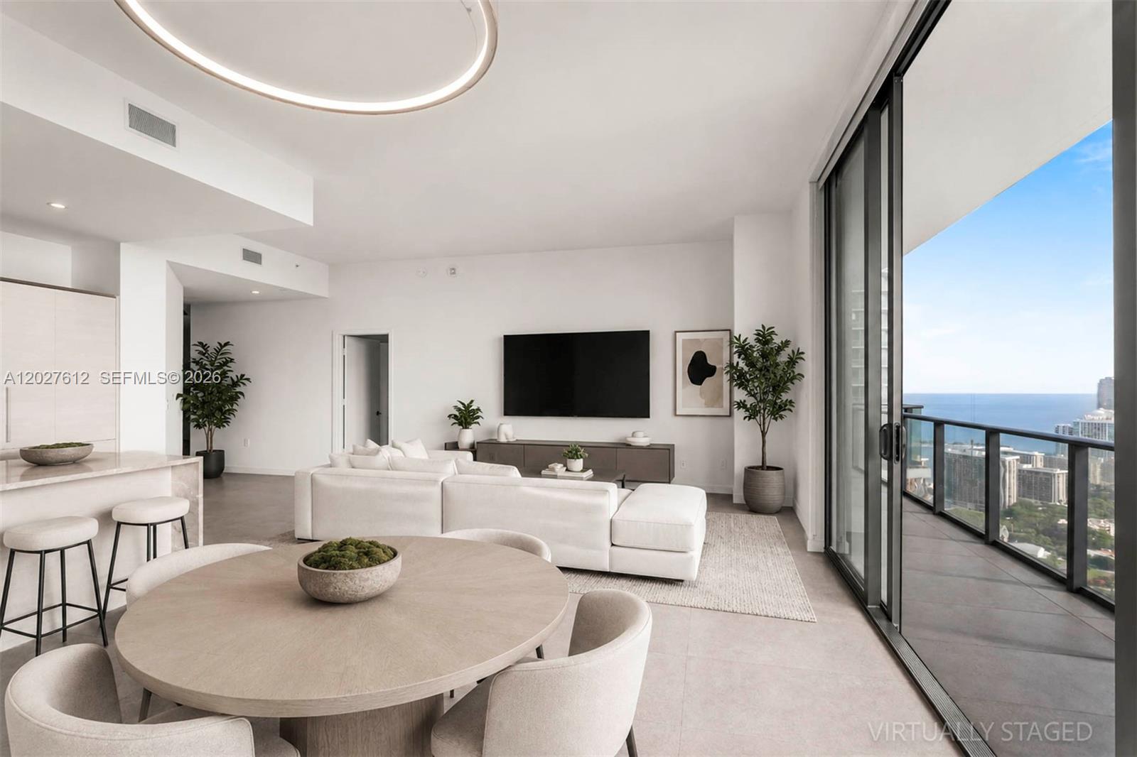 This living and dining area features a white sectional, round table, and balcony with ocean views — 1300 S Miami Ave, Miami FL 33130, MIAMI, FL