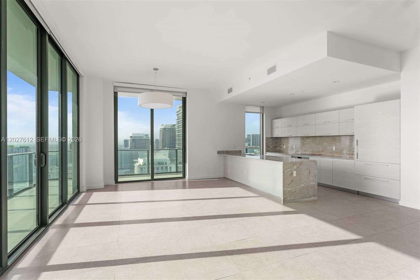 A modern, open-concept kitchen and living area features light tile floors and floor-to-ceiling windows — 1300 S Miami Ave, Miami FL 33130, MIAMI, FL