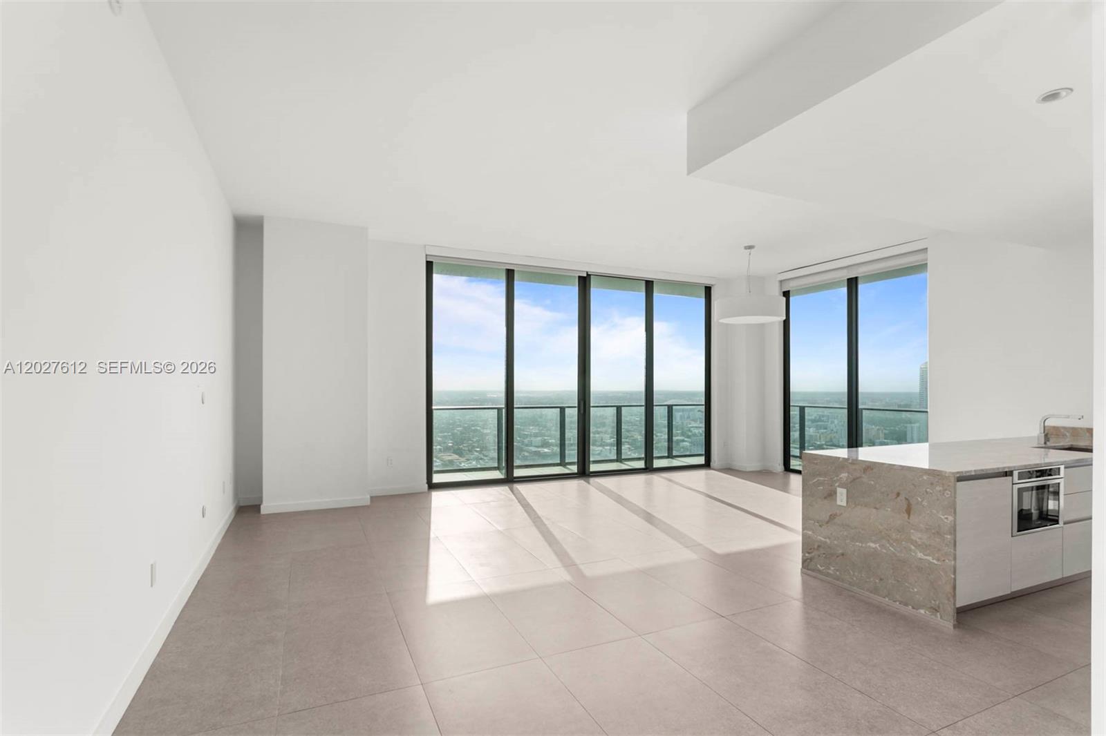 A bright, open-concept living area features floor-to-ceiling windows, tile flooring, and a modern kitchen island — 1300 S Miami Ave, Miami FL 33130, MIAMI, FL