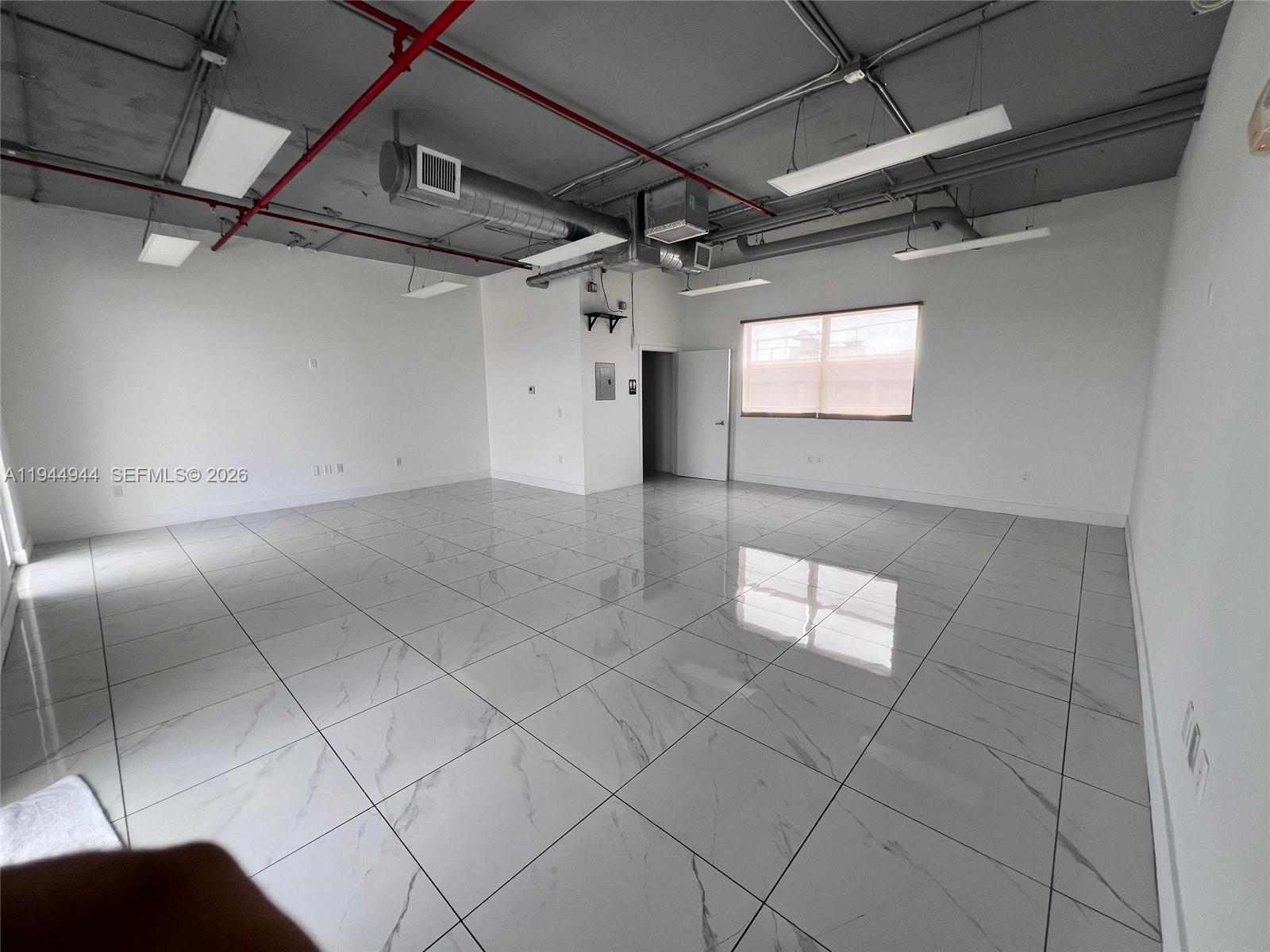 An empty office space features white marble-look tile flooring and an exposed industrial ceiling — 2721 NW 42nd Ave # 203, Miami FL 33142, MIAMI, FL