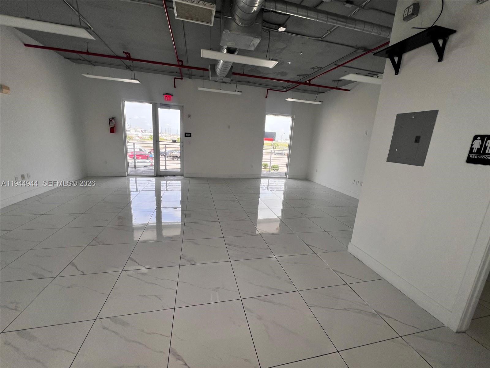 An empty commercial office space features white marble-look tile flooring and an exposed industrial ceiling — 2721 NW 42nd Ave # 203, Miami FL 33142, MIAMI, FL