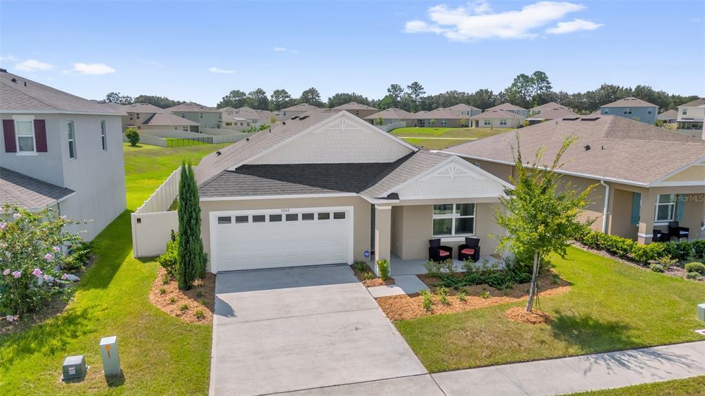 An aerial view shows a single-story suburban house with a two-car garage and lawn — 5242 MAHOGANY DRIVE, MOUNT DORA, FL