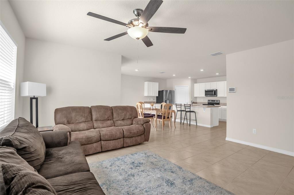 A living room with tile floors and a ceiling fan opens to a kitchen area — 5242 MAHOGANY DRIVE, MOUNT DORA, FL