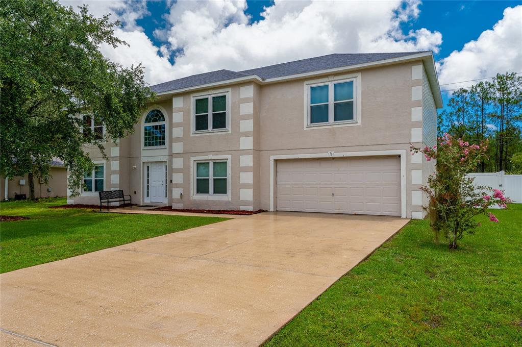 A two-story beige house with a two-car garage and a concrete driveway — 11 ZIRCON COURT, PALM COAST, FL