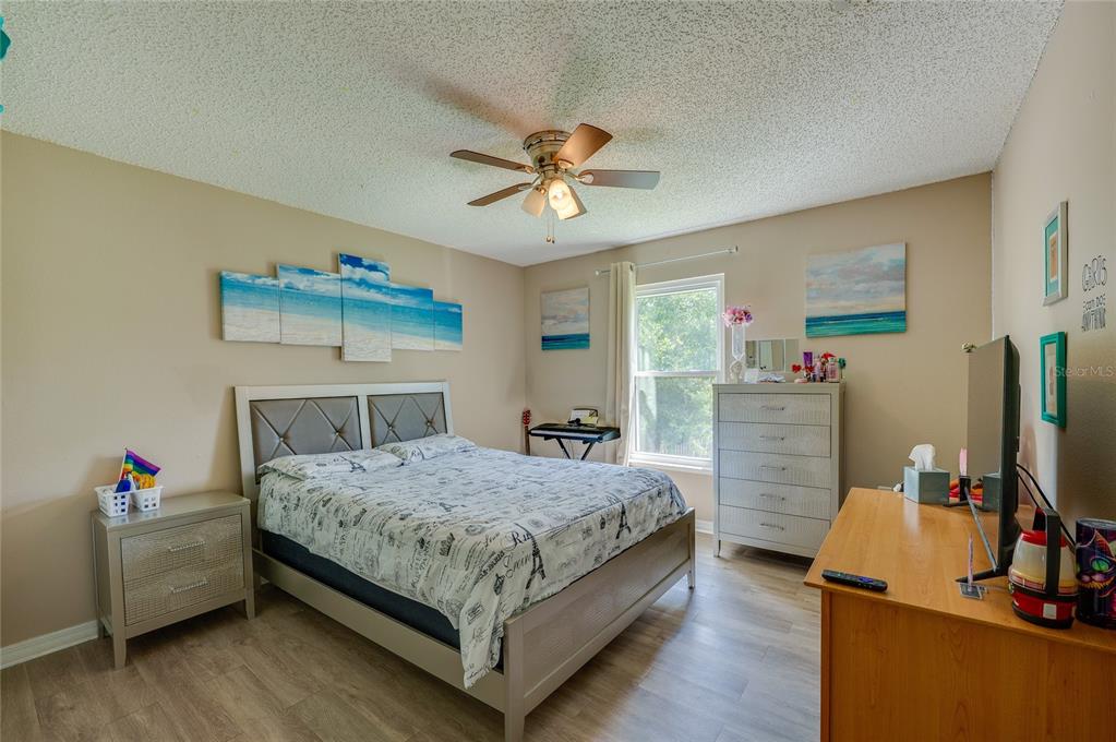 A bedroom features a bed with patterned bedding, a ceiling fan, and light-colored wood flooring — 11 ZIRCON COURT, PALM COAST, FL