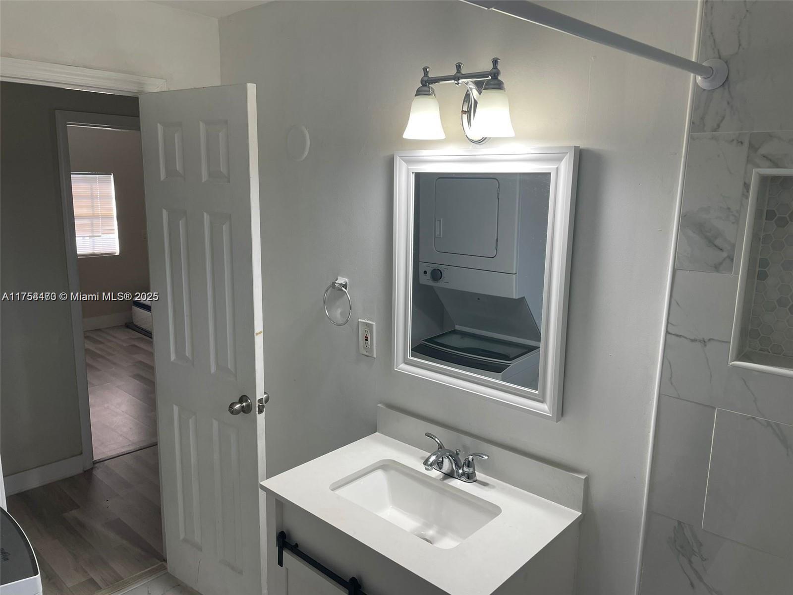 A bathroom features a white vanity, a framed mirror, and a tiled shower area — 4896 SW 28th Ter, Dania Beach FL 33312, DANIA BEACH, FL