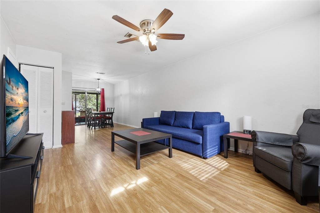 A living room with wood-look flooring, a blue sofa, a coffee table, and a ceiling fan — 4128 NW 44TH DRIVE, GAINESVILLE, FL