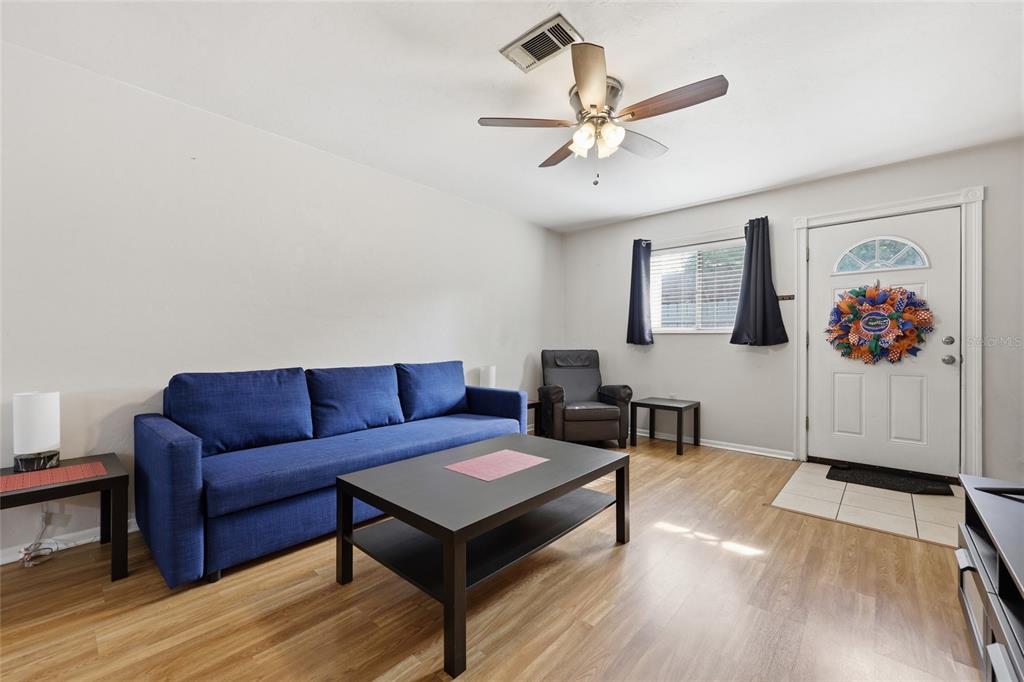 A living room features a blue sofa, a black coffee table, and a front door — 4128 NW 44TH DRIVE, GAINESVILLE, FL