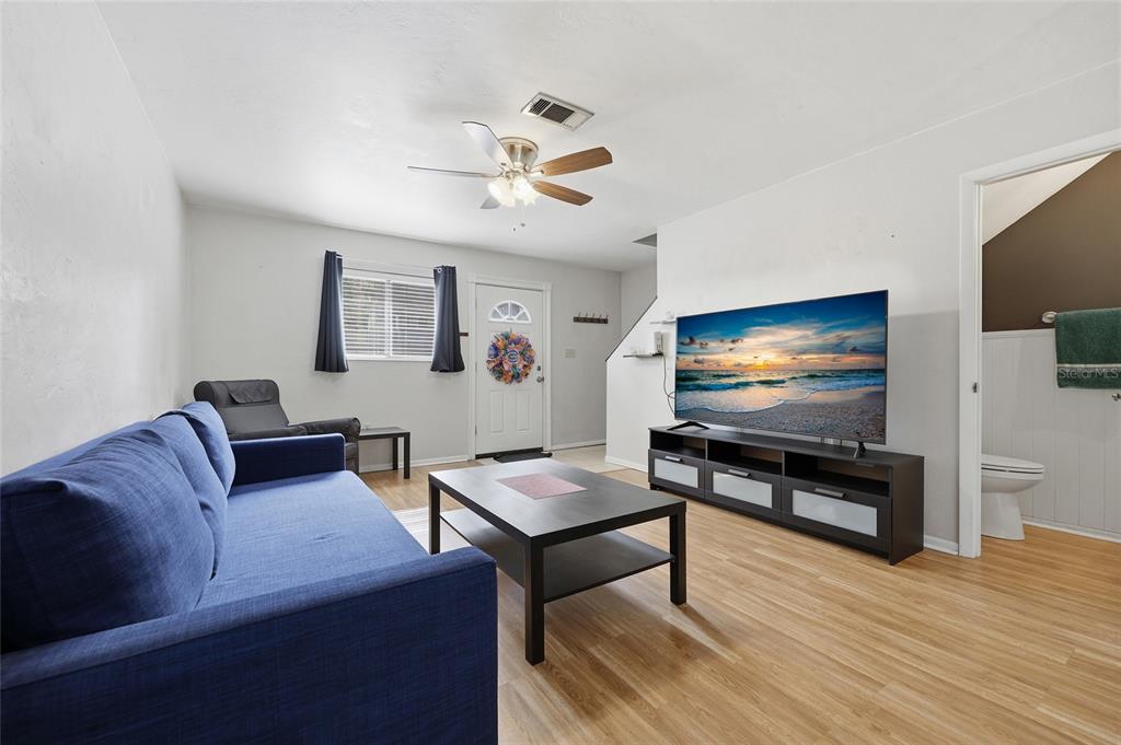 A living room features a blue sofa, a coffee table, a television, and wood flooring — 4128 NW 44TH DRIVE, GAINESVILLE, FL