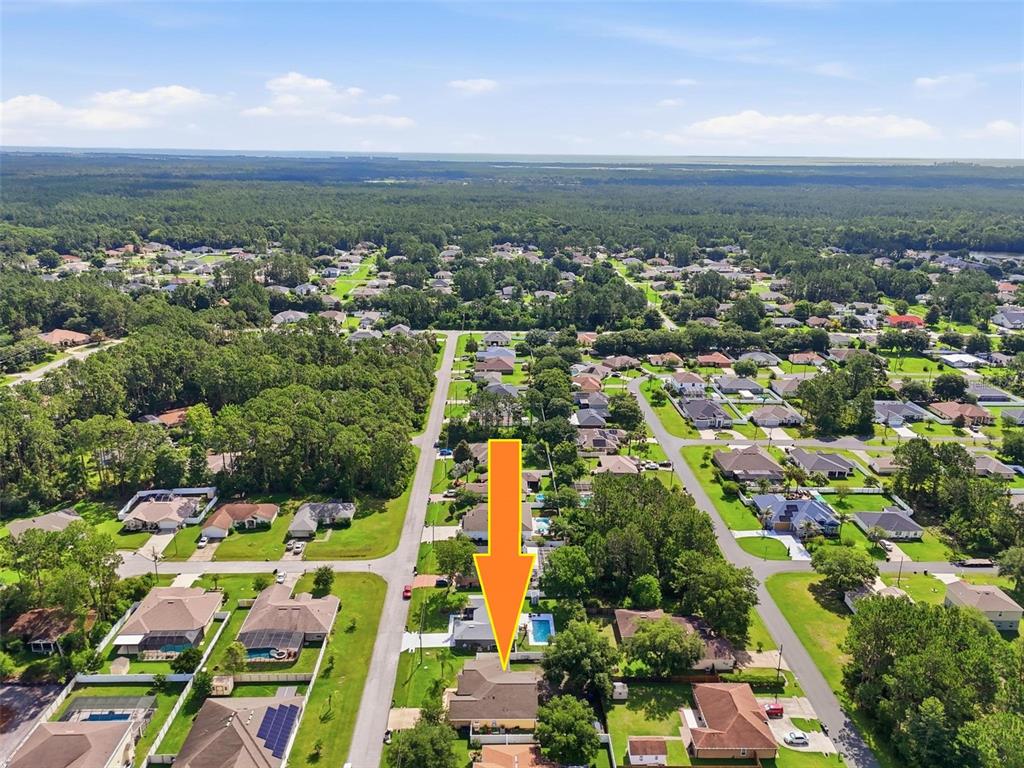An aerial view shows a suburban house with a swimming pool and surrounding neighborhood — 10 LARKSPUR WAY, PALM COAST, FL