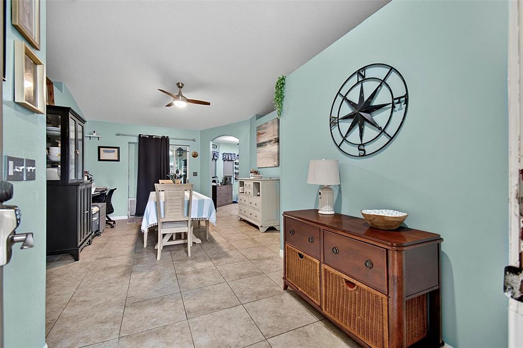 A dining area with tile floors, a wooden sideboard, and a wall-mounted compass decoration — 10 LARKSPUR WAY, PALM COAST, FL