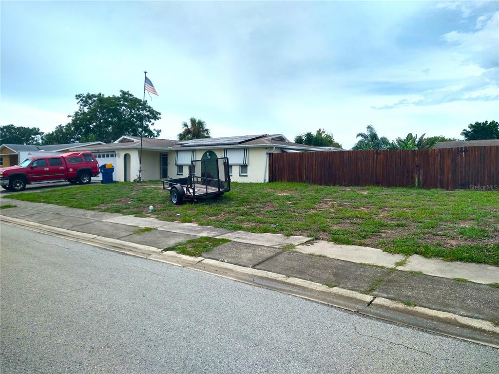 A single-story house with a wooden fence, a trailer, and a red truck parked outside — 6325 KENTFIELD AVENUE, NEW PORT RICHEY, FL