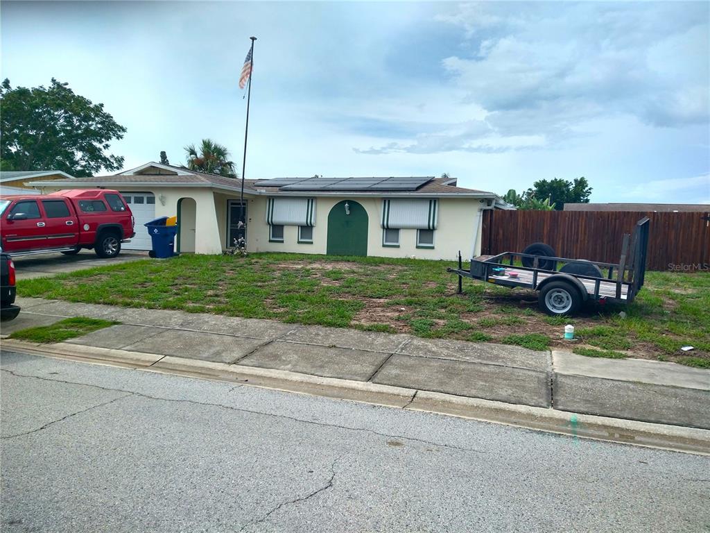 A single-story house with a red truck, a utility trailer, and solar panels on the roof — 6325 KENTFIELD AVENUE, NEW PORT RICHEY, FL