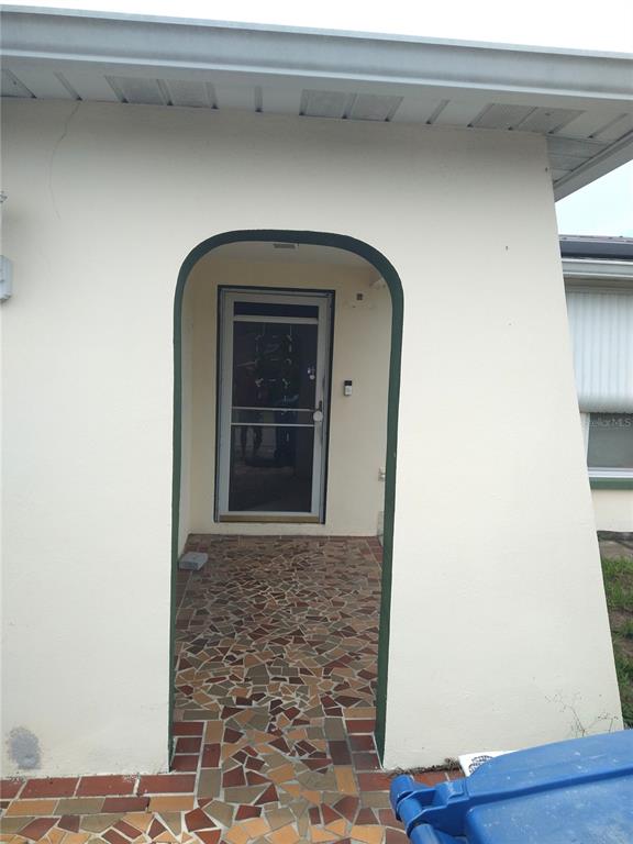 An arched entryway leads to a front door with a screen door and tiled porch — 6325 KENTFIELD AVENUE, NEW PORT RICHEY, FL