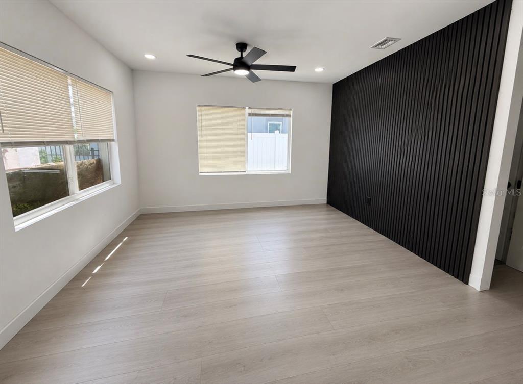 An empty room features light wood-look flooring, white walls, and a black slatted accent wall — 3010 6TH AVENUE S, ST PETERSBURG, FL