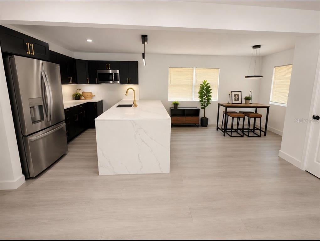 A modern kitchen features black cabinets, a white marble-topped island, and a dining area — 3010 6TH AVENUE S, ST PETERSBURG, FL