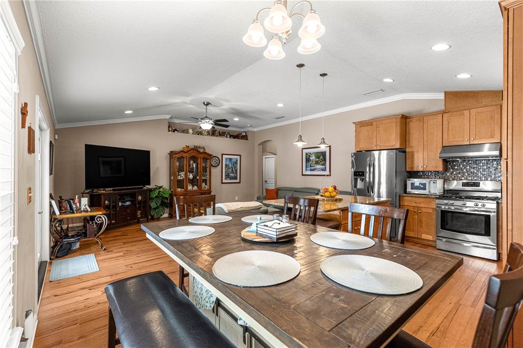 A dining area with a wooden table sits in an open-concept kitchen and living space — 4328 CHOKEBERRY, MIDDLEBURG, FL