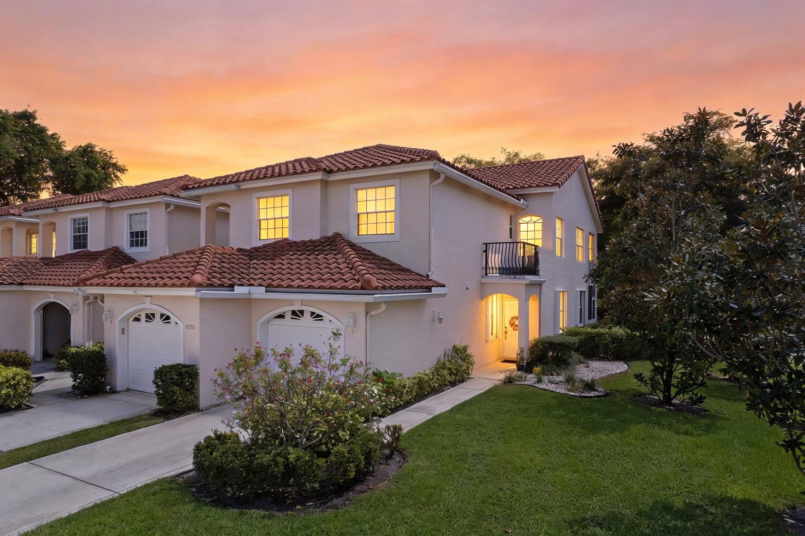 A two-story stucco townhouse with a tile roof and a small balcony at sunset — 8550 Via Romana # 1, Boca Raton FL 33496, BOCA RATON, FL