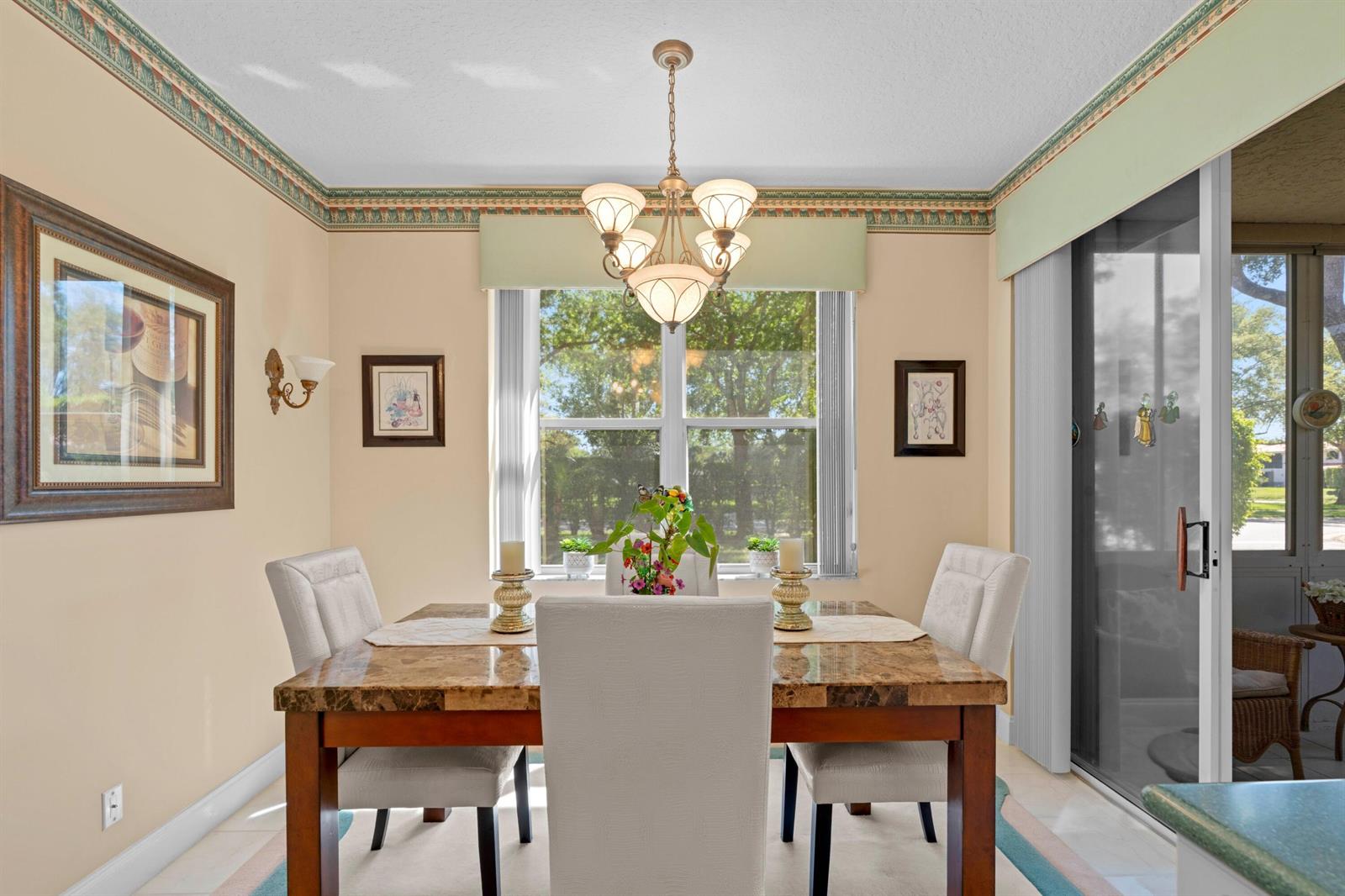 A dining room features a marble-topped table, upholstered chairs, a chandelier, and a sliding door — 8550 Via Romana # 1, Boca Raton FL 33496, BOCA RATON, FL