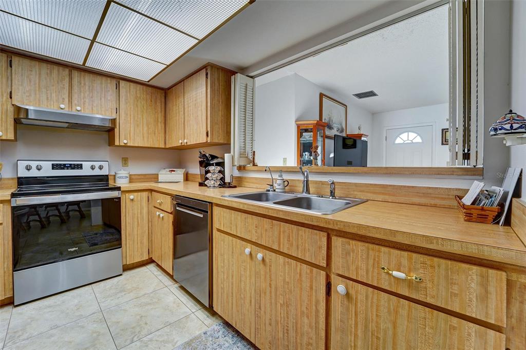 A kitchen with wood-grain cabinets, laminate countertops, stainless steel appliances, and a pass-through window — 11340 DOLLAR LAKE DRIVE UNIT 2, PORT RICHEY, FL