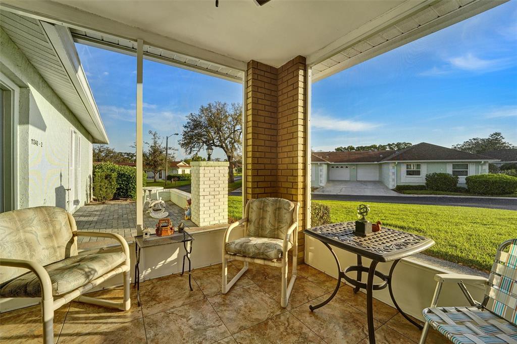A screened-in porch with tile flooring, patio furniture, and a view of a neighborhood street — 11340 DOLLAR LAKE DRIVE UNIT 2, PORT RICHEY, FL
