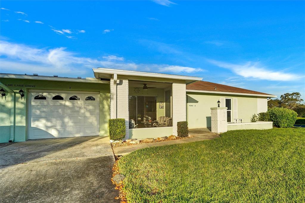 A light green single-story house features a white garage door and a covered front porch — 11340 DOLLAR LAKE DRIVE UNIT 2, PORT RICHEY, FL