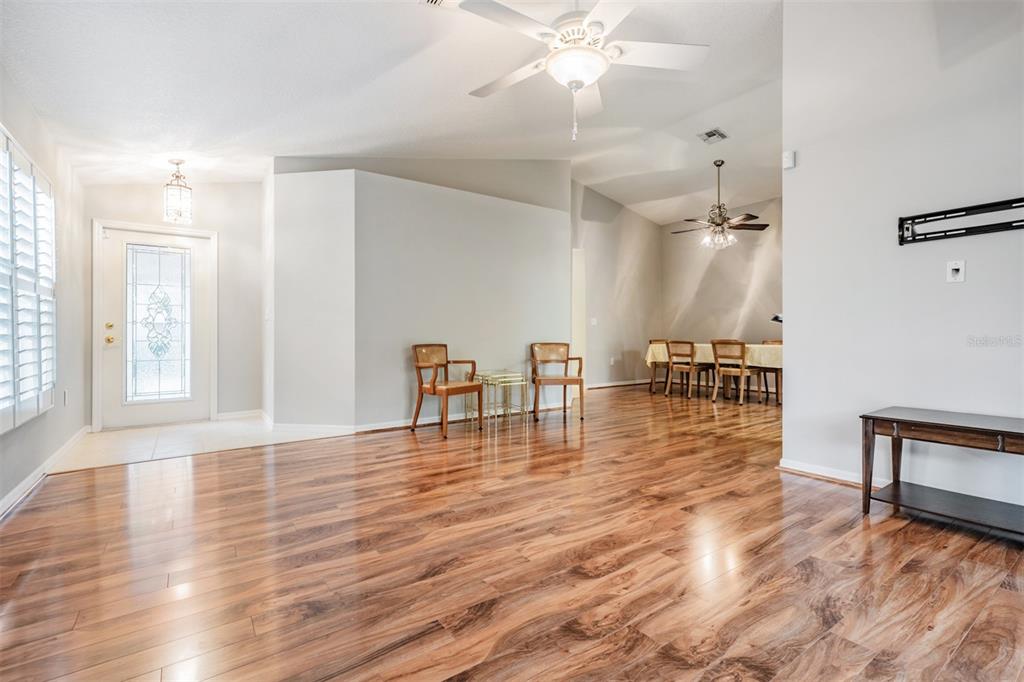 A bright living and dining area features wood-look flooring, vaulted ceilings, and two ceiling fans — 10230 OLD TAMPA BAY DRIVE, SAN ANTONIO, FL