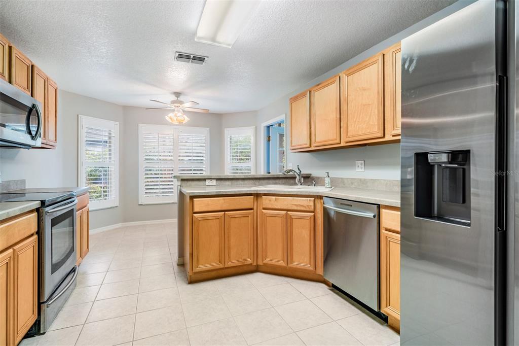 A kitchen with light wood cabinets, stainless steel appliances, and tile flooring — 10230 OLD TAMPA BAY DRIVE, SAN ANTONIO, FL