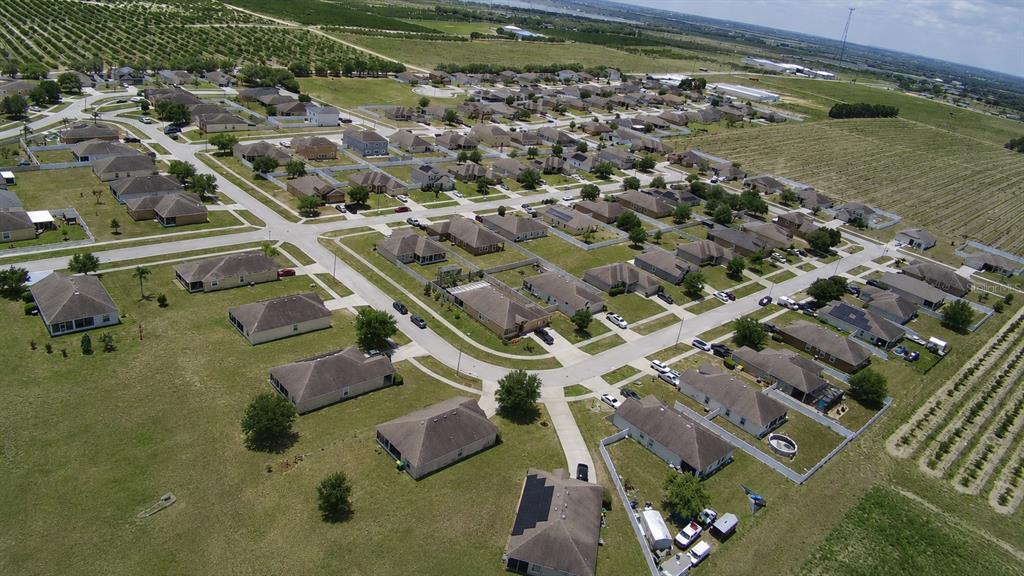 An aerial view shows a suburban neighborhood with single-family homes surrounded by agricultural fields — 3300 LYNROCK AVENUE, DUNDEE, FL