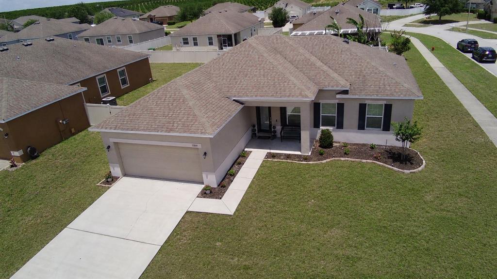 An aerial view shows a single-story suburban house with a tan exterior, shingled roof, and garage — 3300 LYNROCK AVENUE, DUNDEE, FL