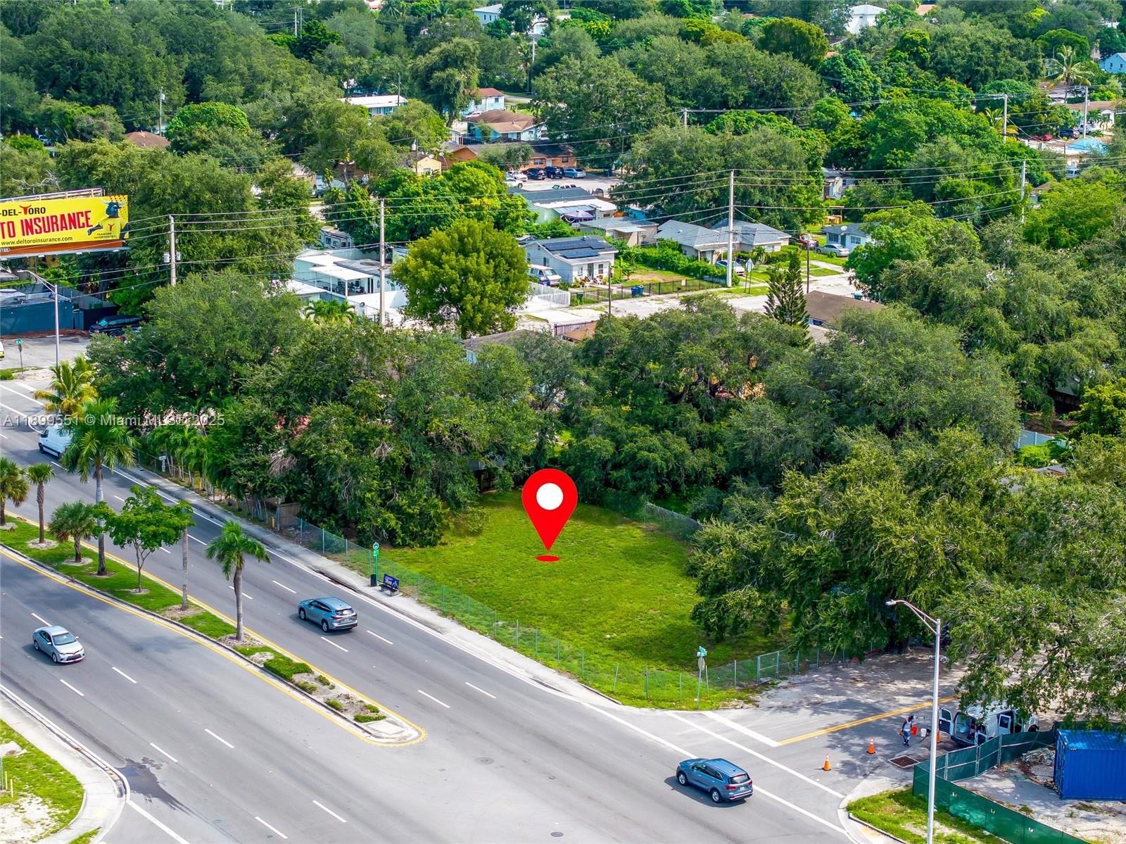 An aerial view shows a vacant, fenced grassy lot situated along a multi-lane road — 90 2200, Miami FL 33147, MIAMI, FL