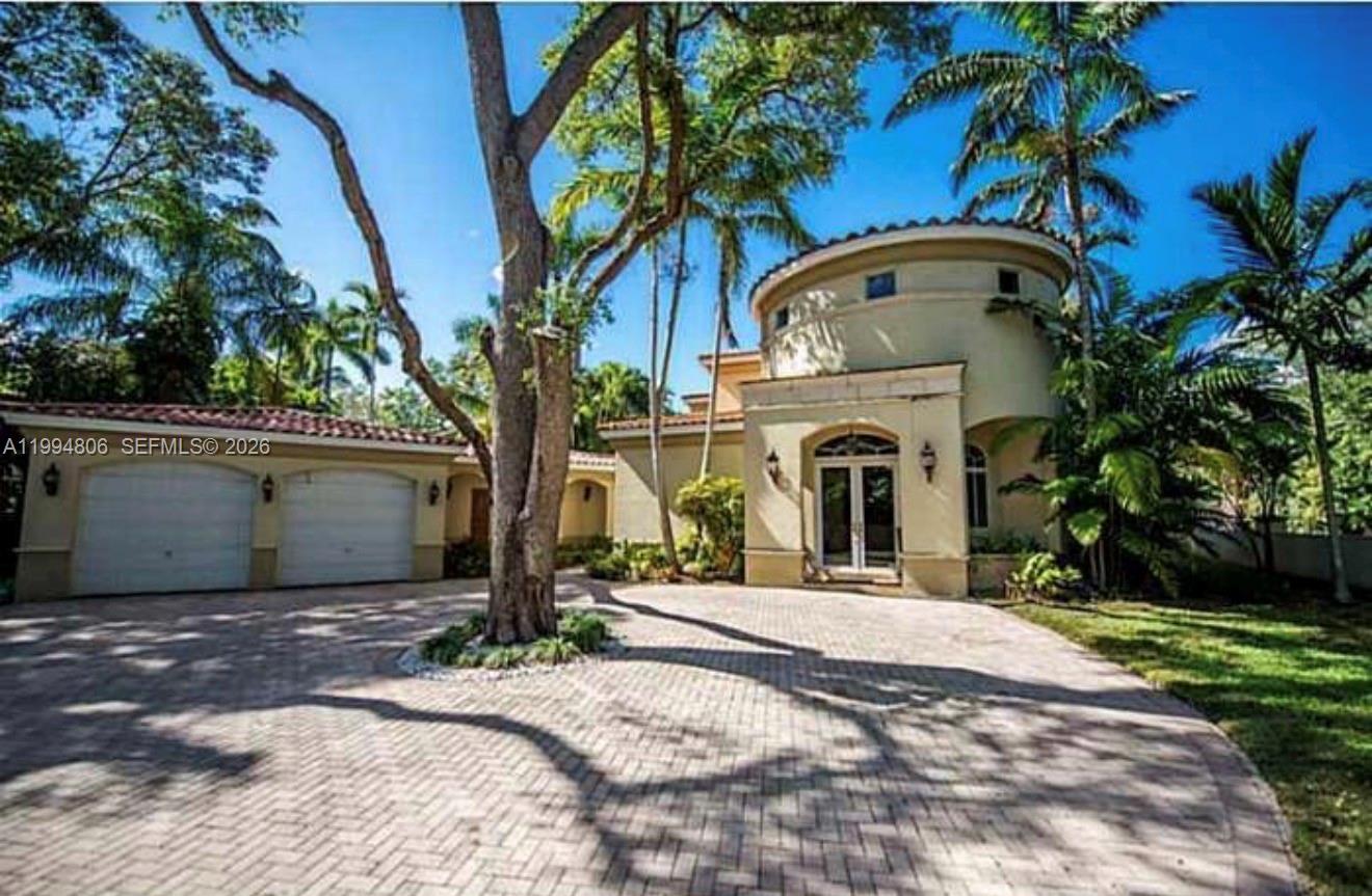 A beige house with a circular tower, a paved driveway, and a large central tree — 3630 Justison Rd, Miami FL 33133, MIAMI, FL