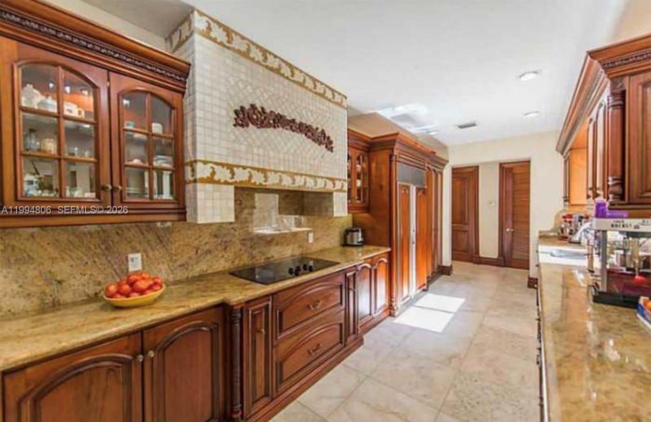 A kitchen features dark wood cabinetry, granite countertops, and a tiled range hood — 3630 Justison Rd, Miami FL 33133, MIAMI, FL