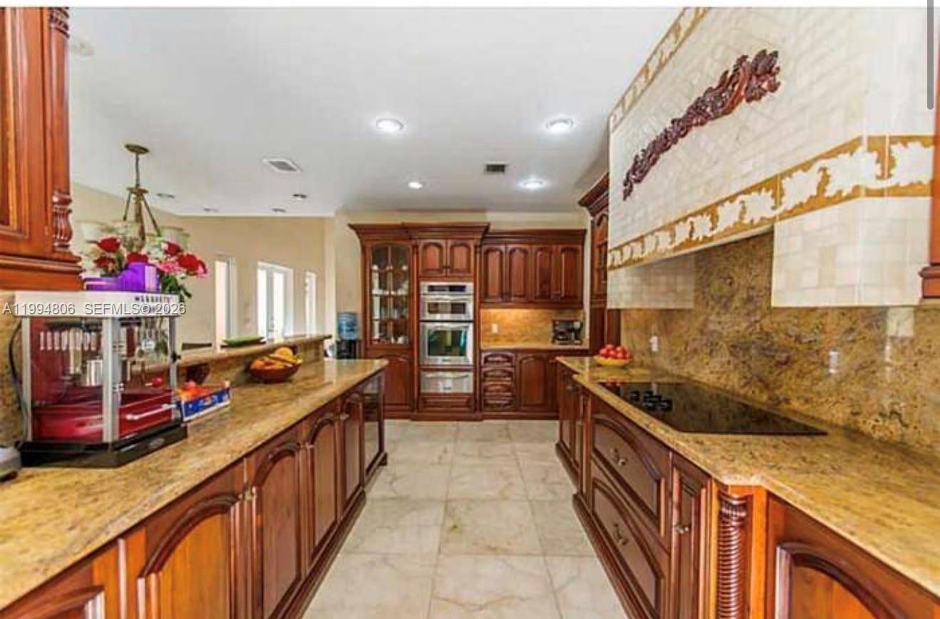 A kitchen features dark wood cabinetry, granite countertops, a built-in oven, and a cooktop — 3630 Justison Rd, Miami FL 33133, MIAMI, FL