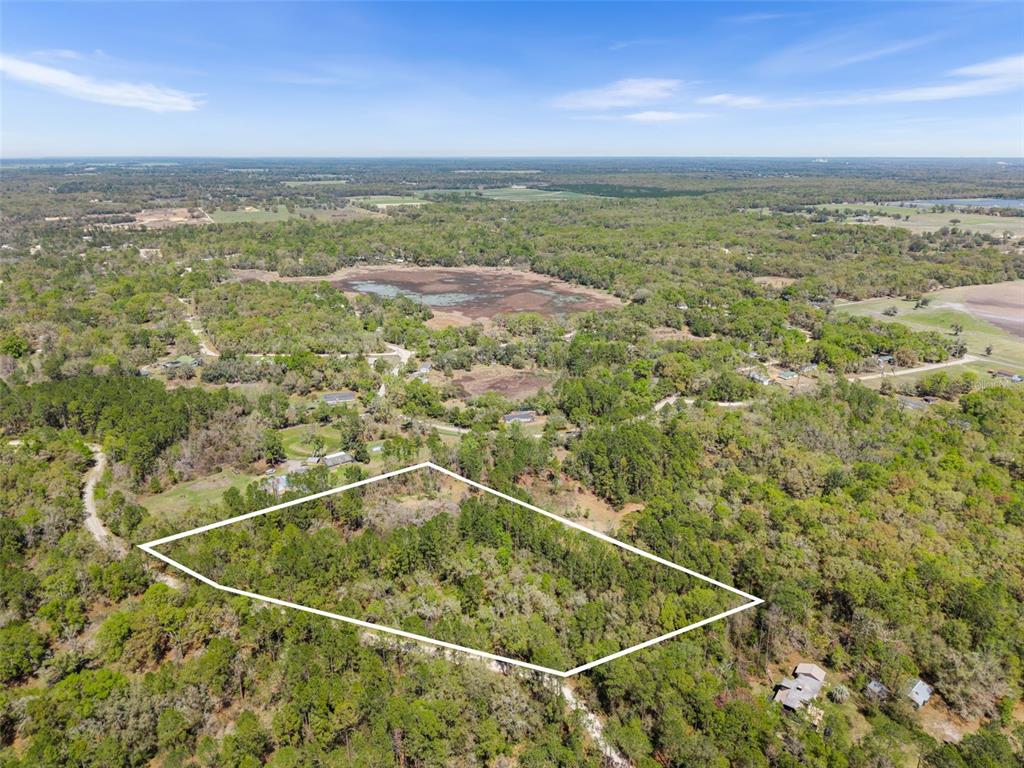 An aerial view shows a wooded, rectangular plot of land outlined in white — 0 SE 91ST TRAIL, TRENTON, FL