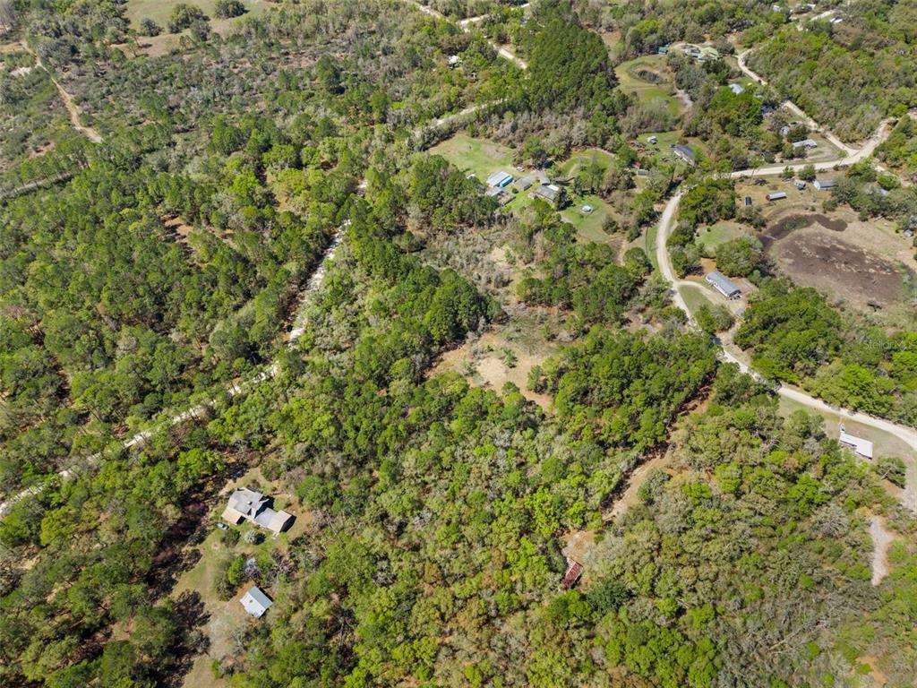 An aerial view shows a rural property with scattered houses, dense trees, and dirt roads — 0 SE 91ST TRAIL, TRENTON, FL